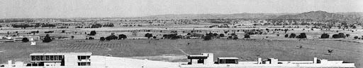 A wide shot in black and white image of Chandigarh, a city in India, before construction began so there is dirt land and the roof of a building