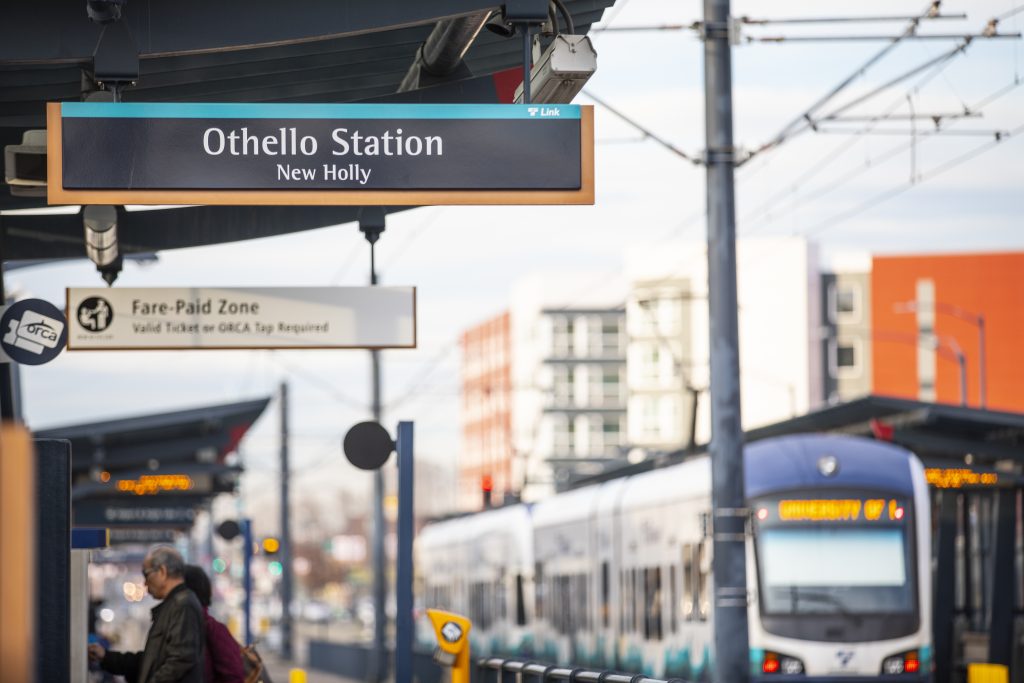 Othello lightrail station with train in the background and people buying tickets