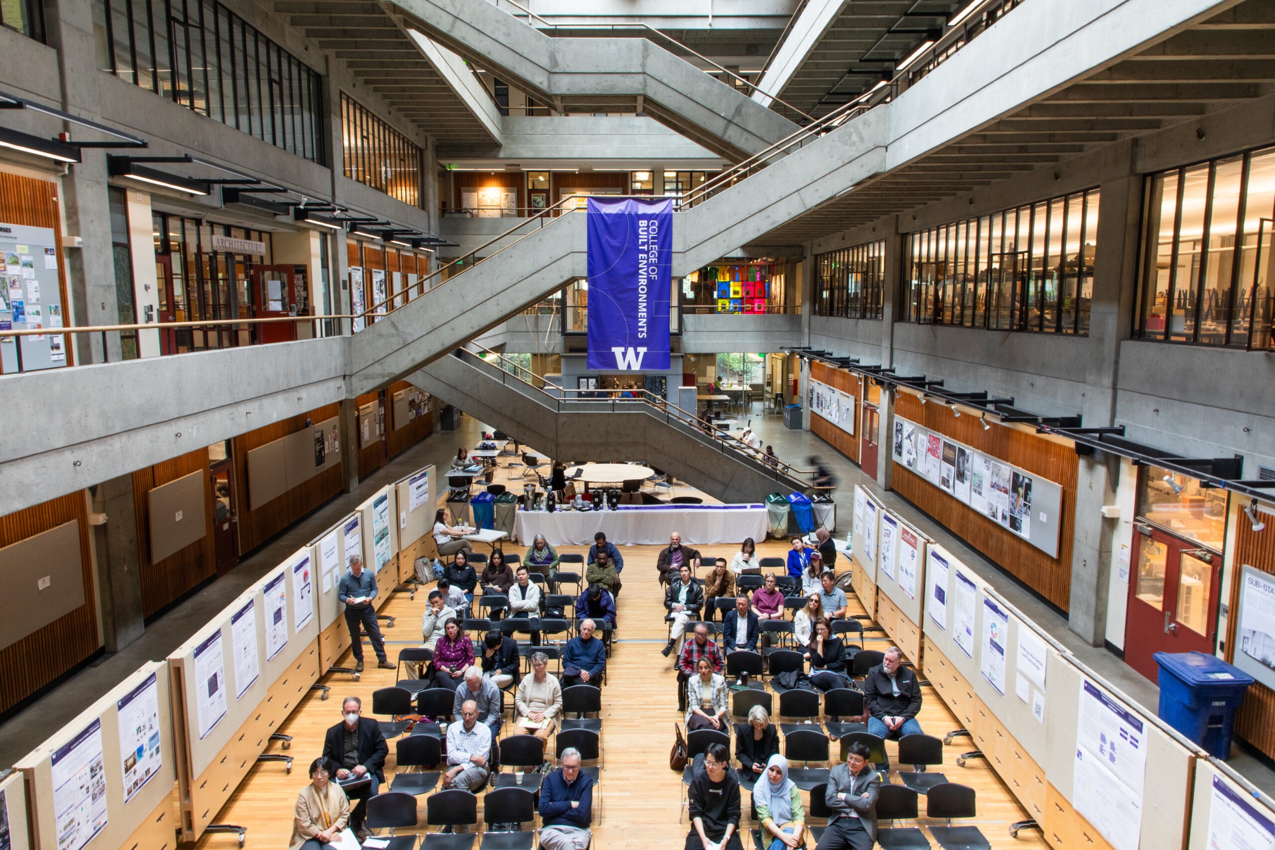 Wide view of attendees sitting in Gould Court, surrounded by research posters